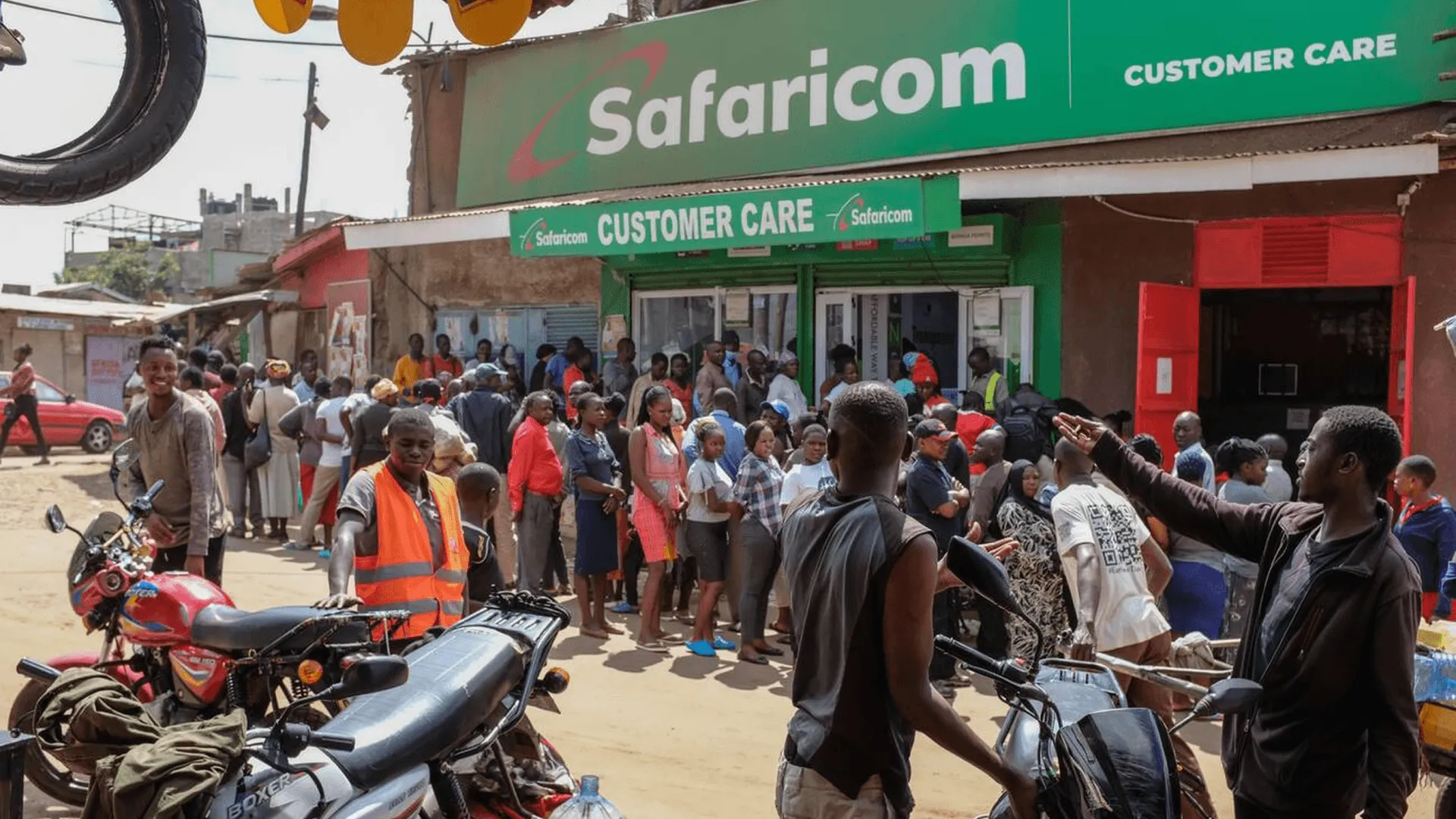 A crowd queuing outside a Safaricom Customer Care centre, with motorbikes parked in the street.