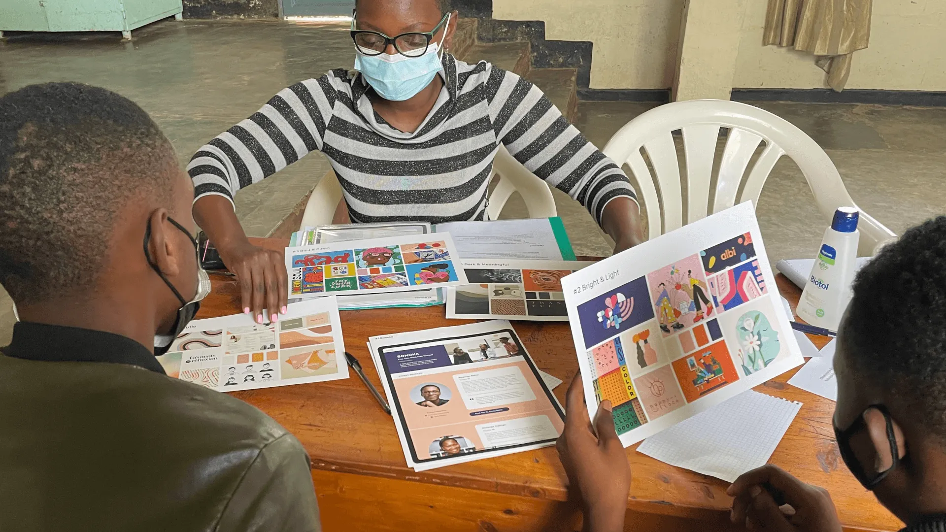 Participants in a co-design workshop sit around a table covered in printed design boards.